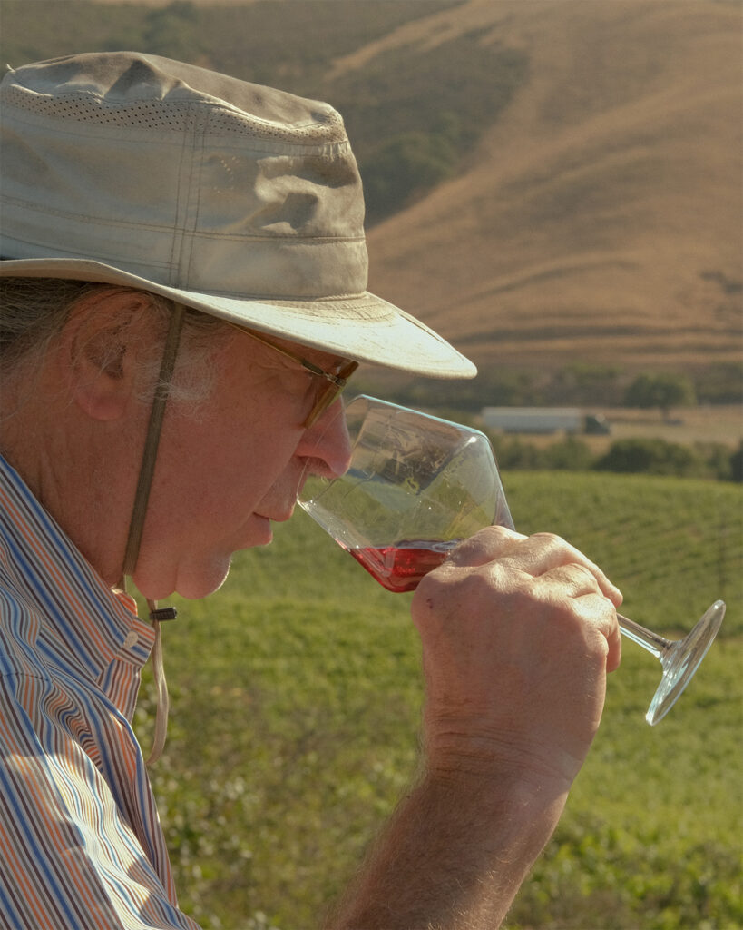 Randall Grahm drinking red wine in the vineyard